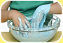 Photograph shows a pair of hands mixing a concoction of blue goo in a mixing bowl
