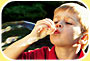 Photograph shows a boy blowing a large soap bubble